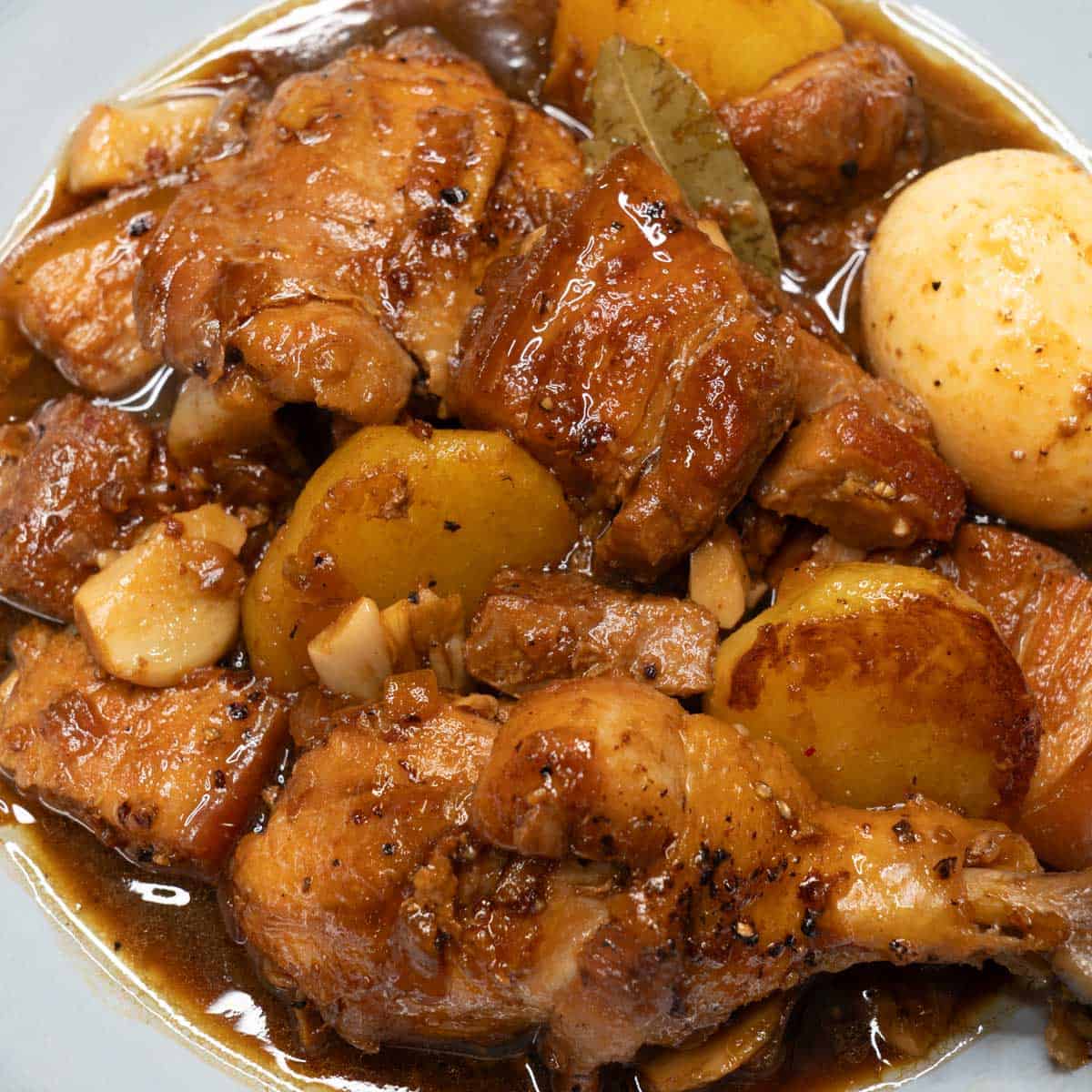 Chicken and pork adobo (with potatoes and eggs) served in a bowl.