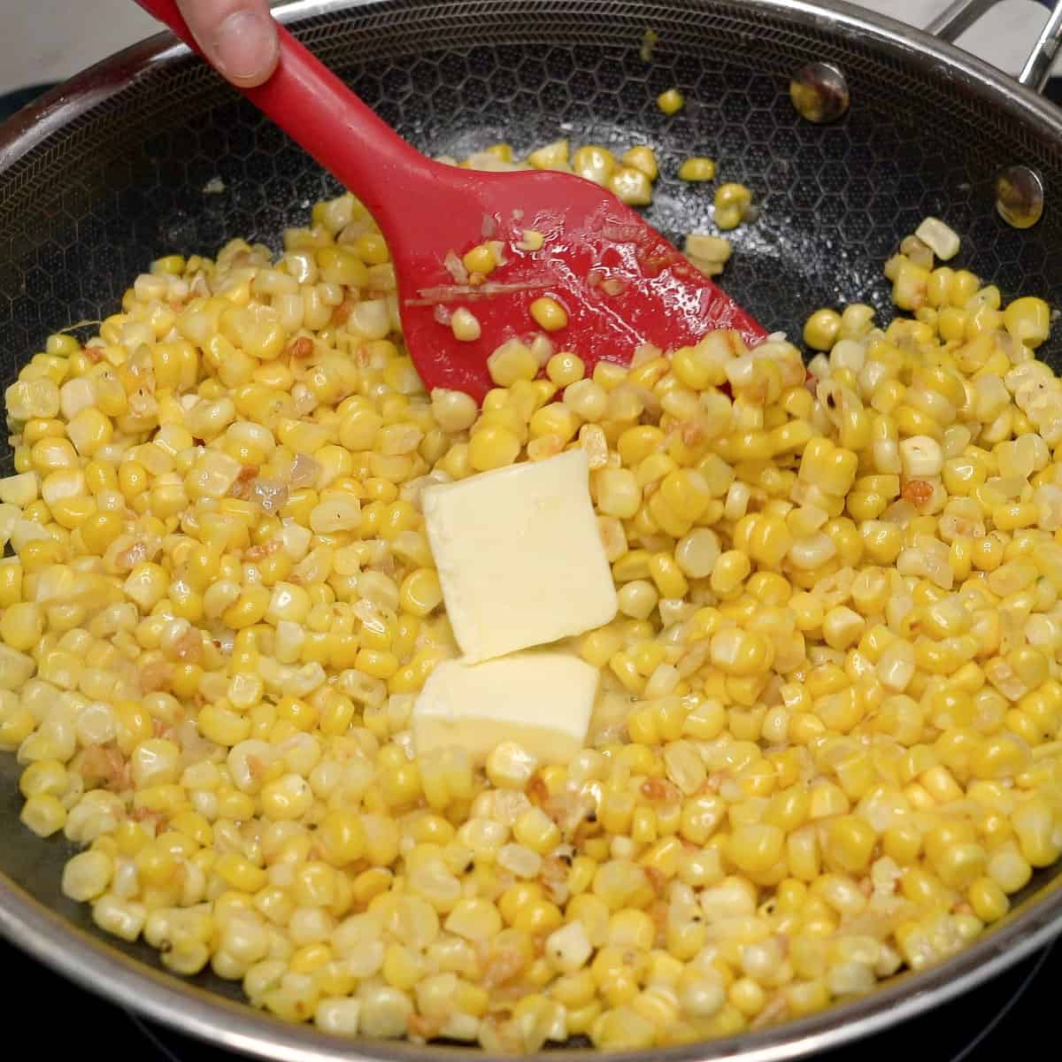Adding butter to sauteed corn.
