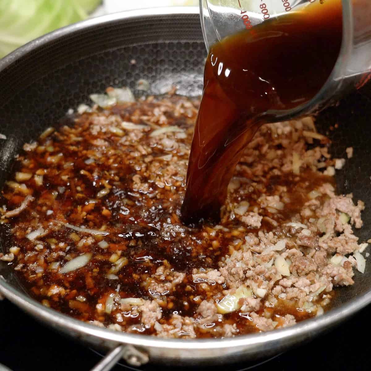 Pouring the sauce over the browned meat and aromatics.
