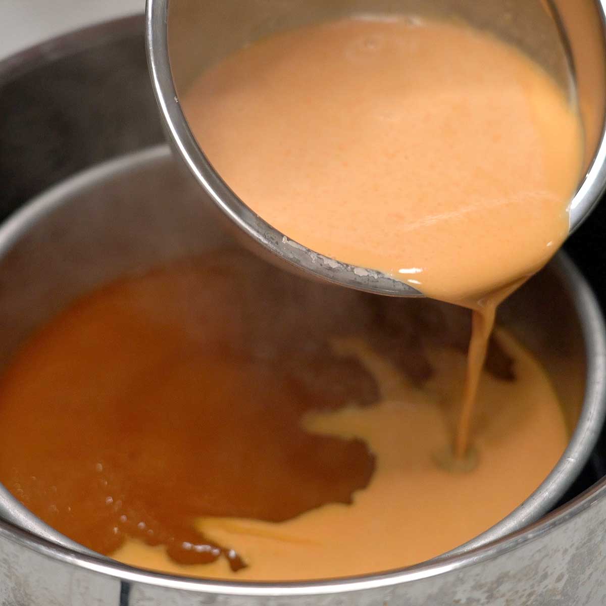 Pouring the kutsinta top layer batter over the partially cooked bottom layer.
