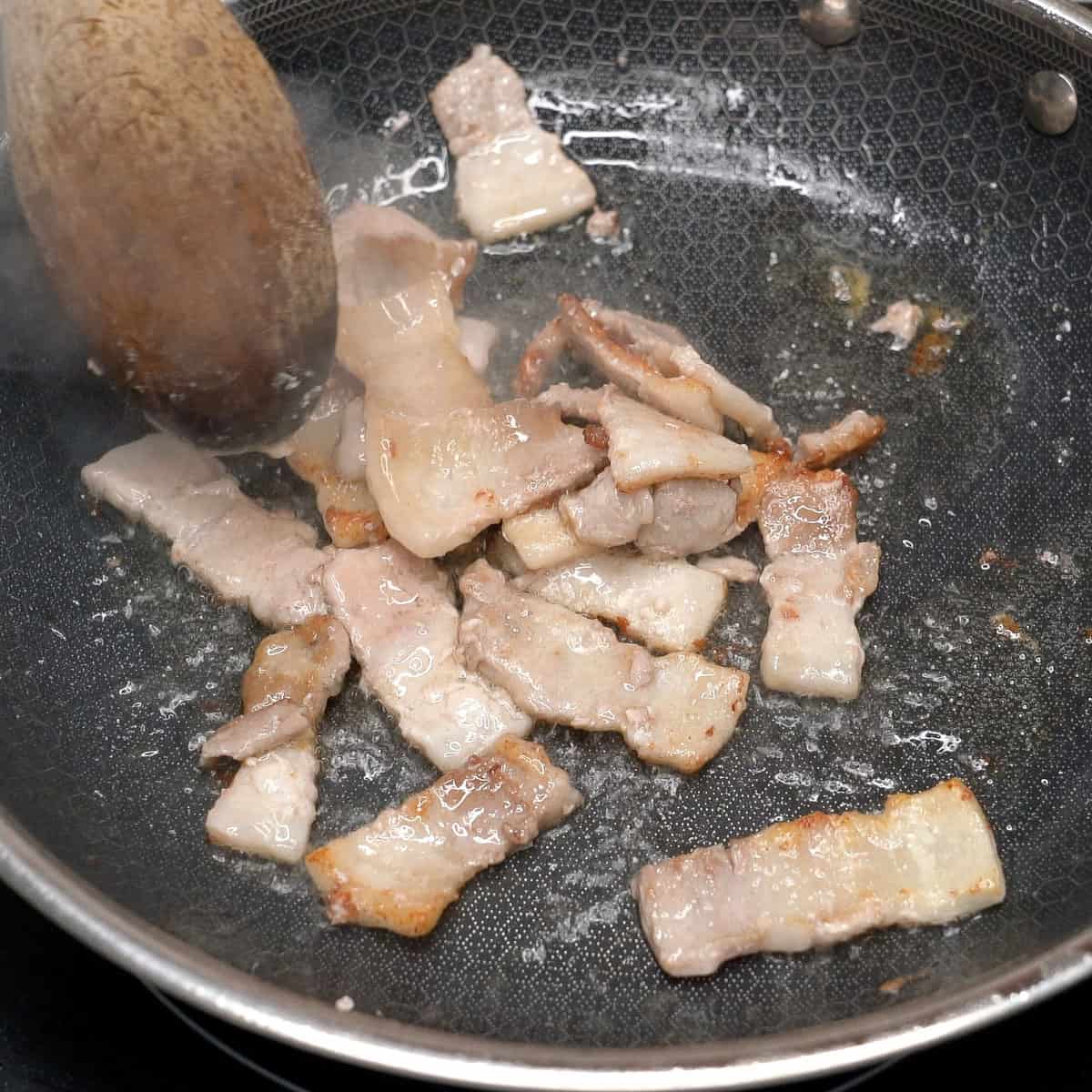 Browning pork belly in a pan.