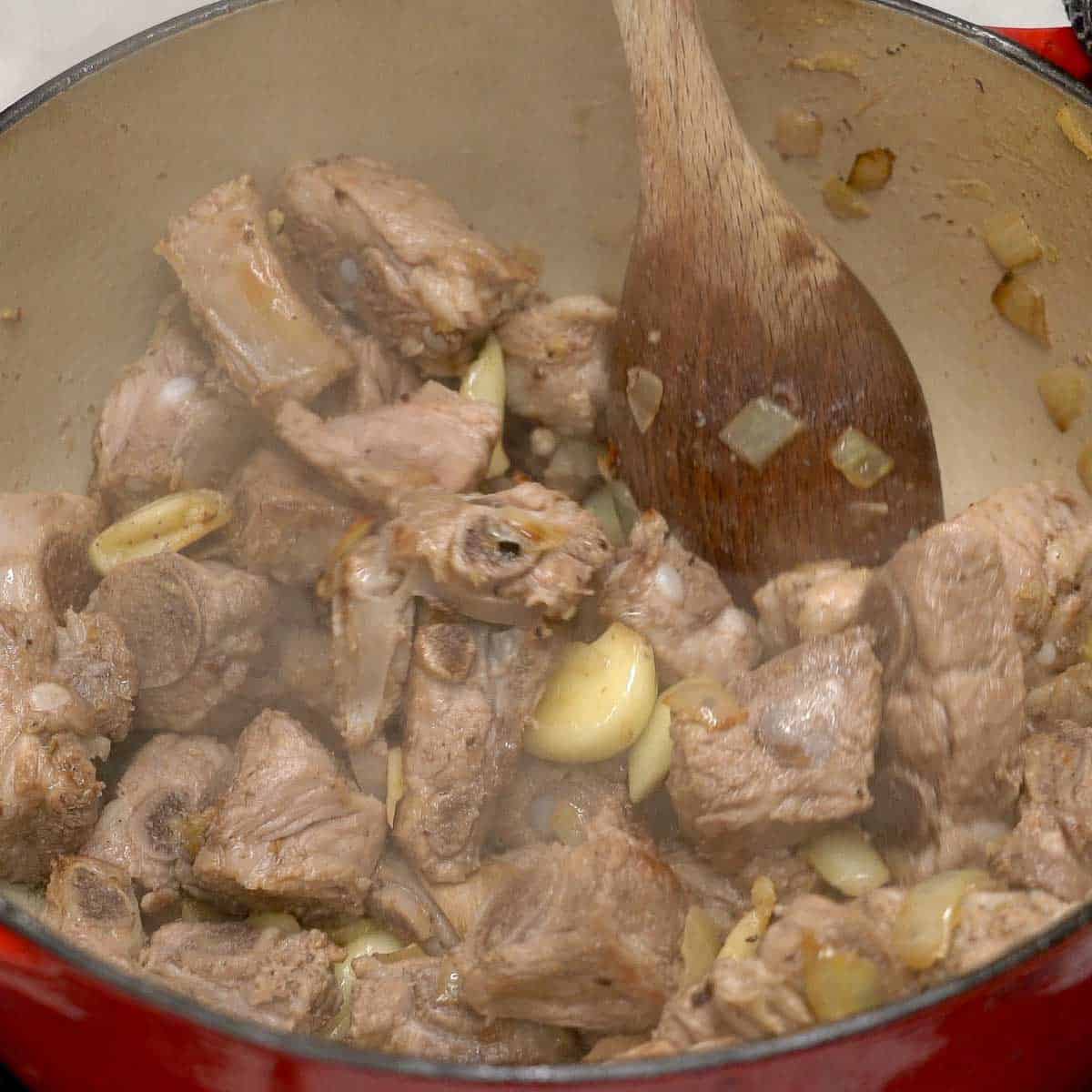 Browning the ribs with aromatics in the pot.