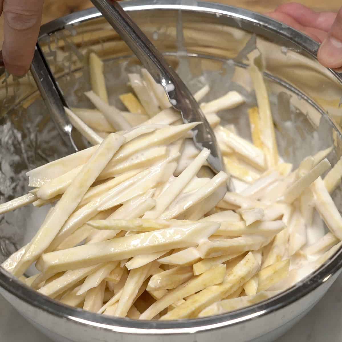 Coating the sweet potatoes with the batter.