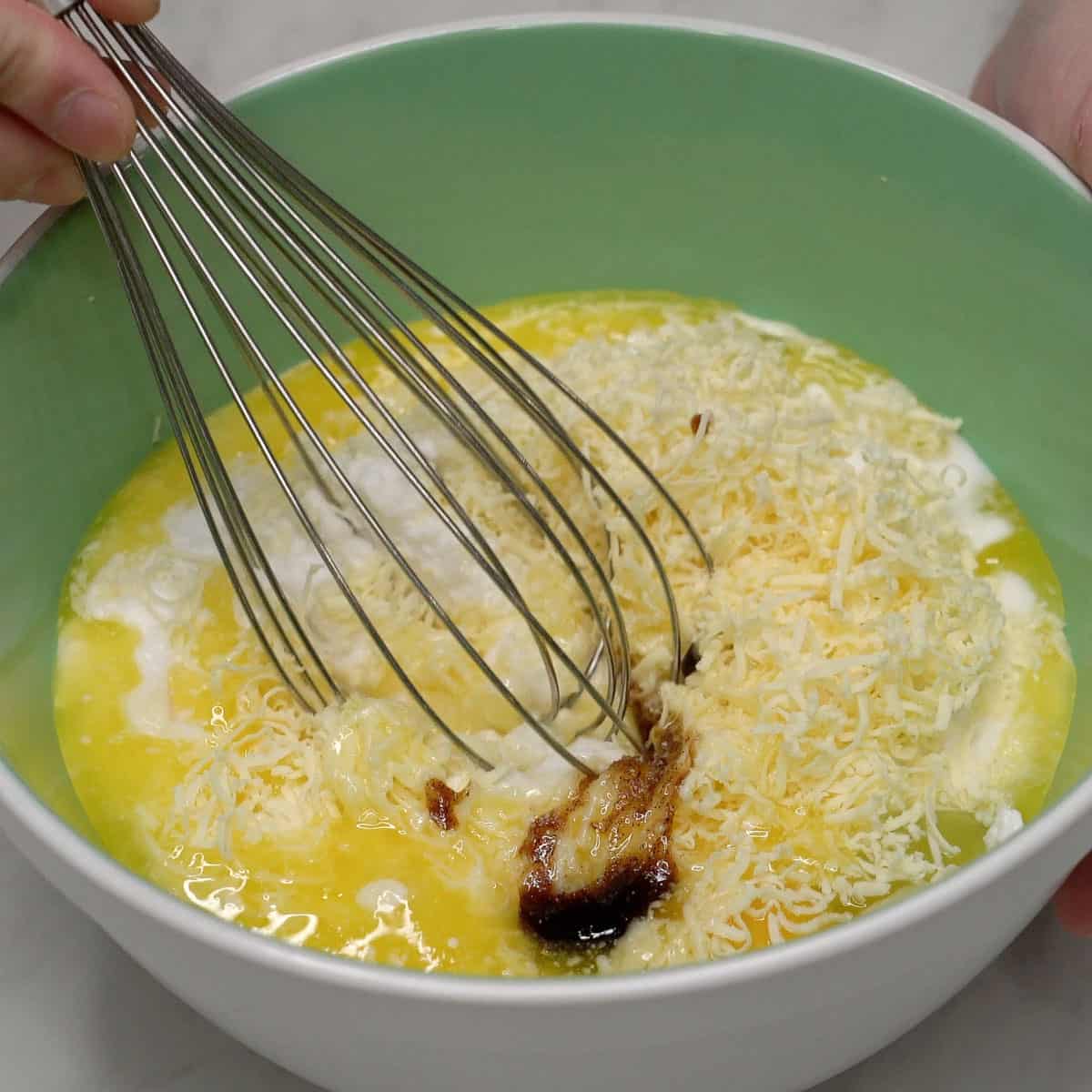 Mixing the cassava cake (budin) ingredients in a bowl.