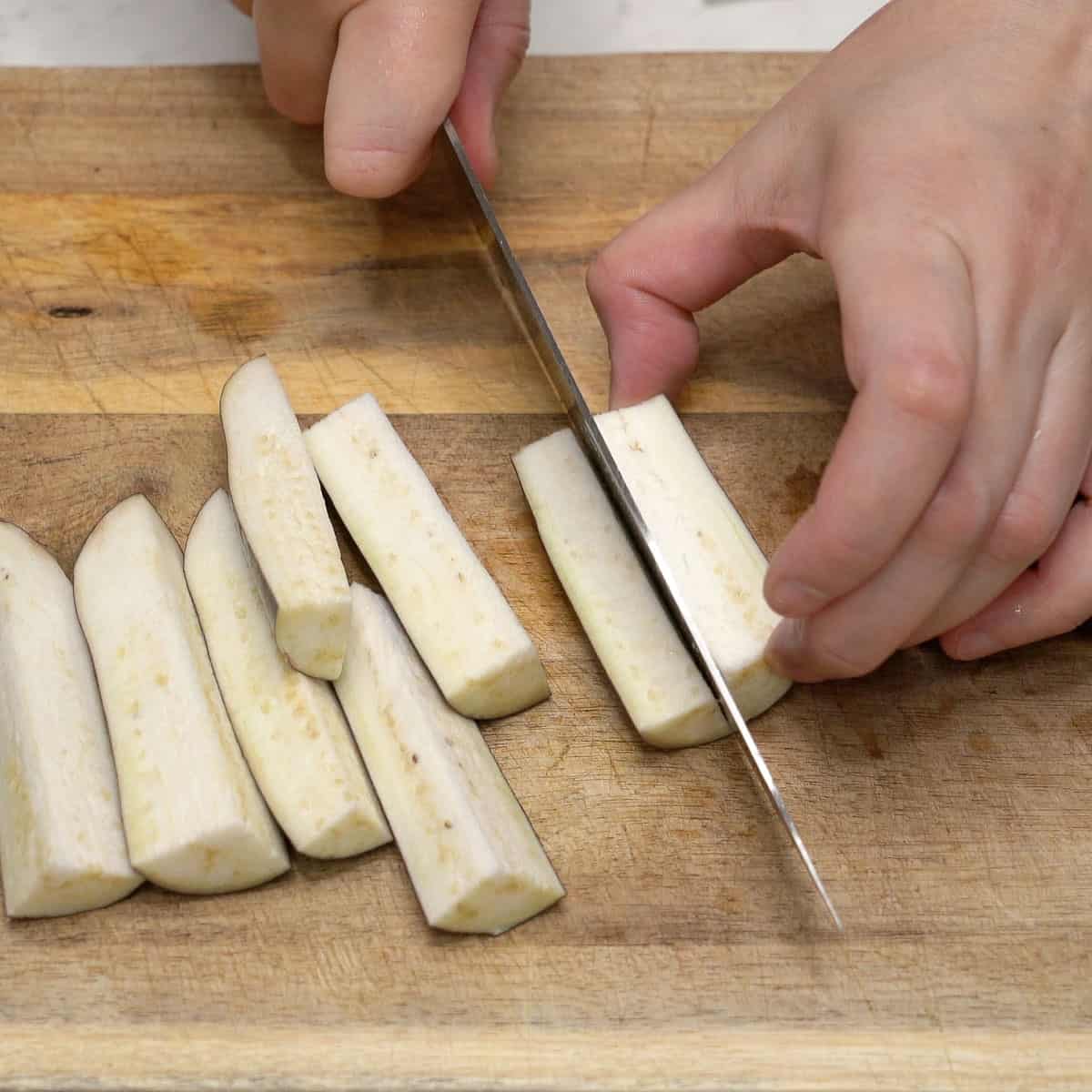 Cutting the eggplant into pieces.