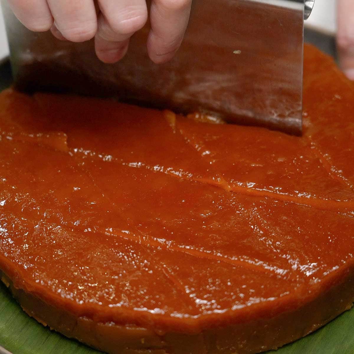 Slicing the kutsinta on a banana leaf-lined plate.