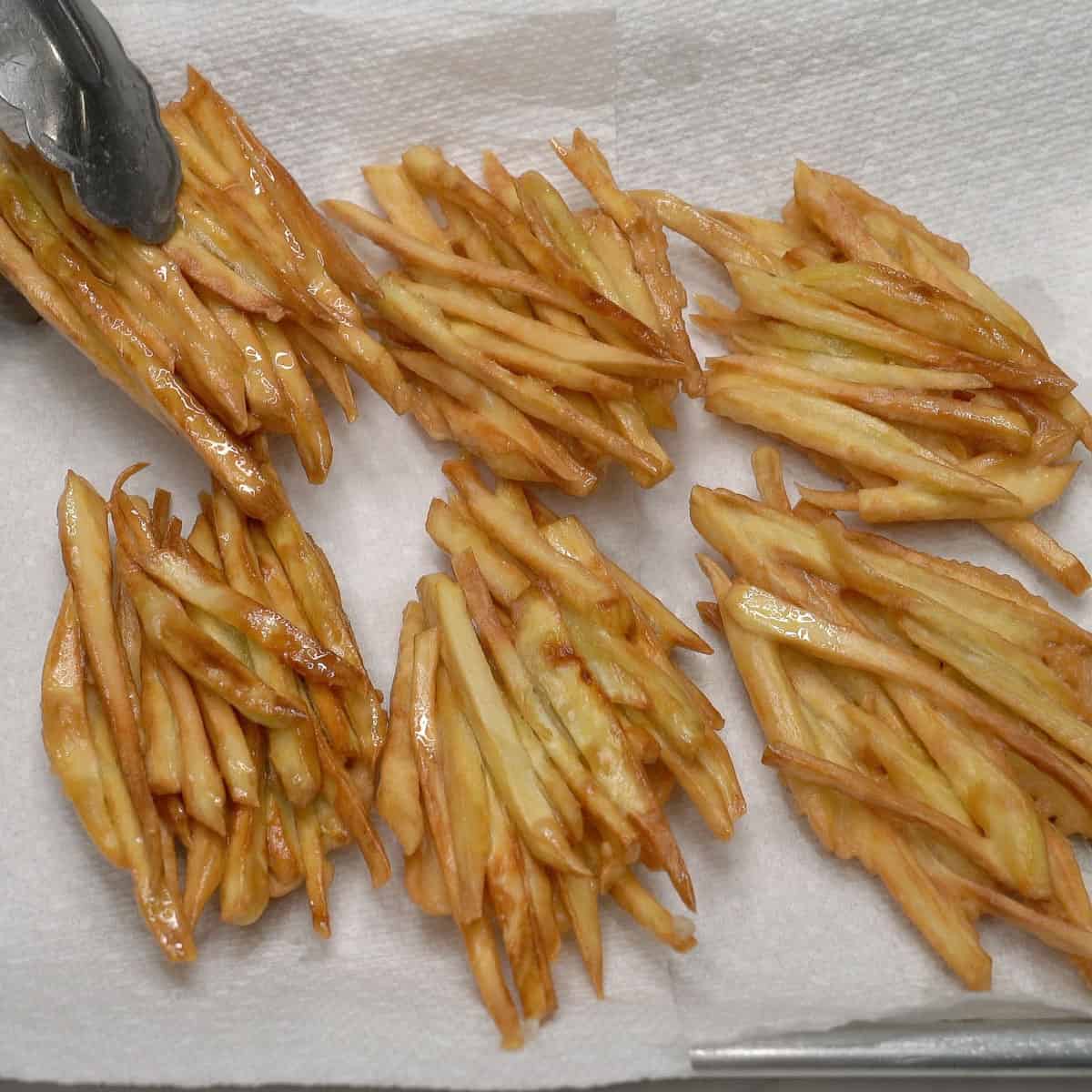 Draining the sweet potato fritters on paper towels.