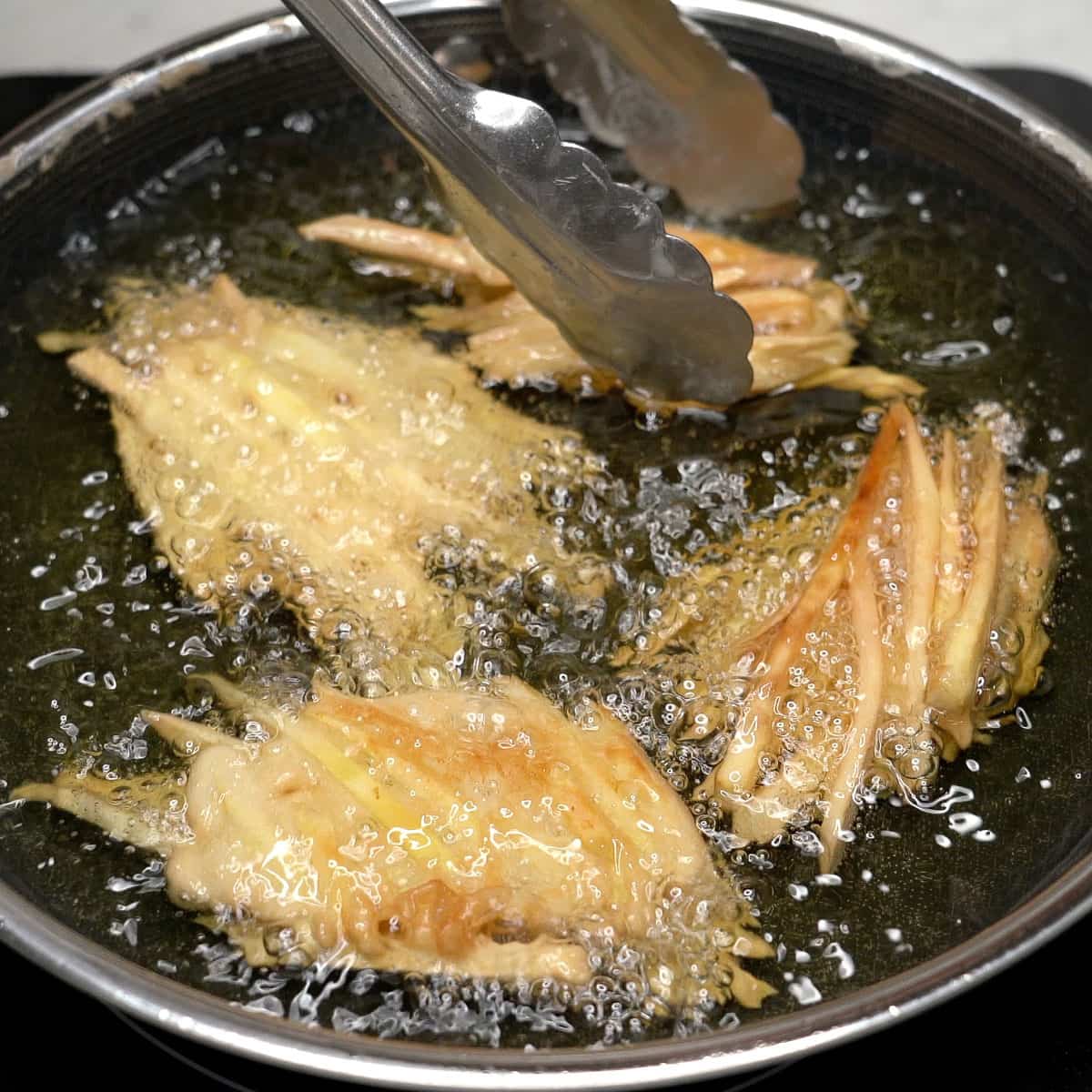 Frying the sweet potato fritters in oil.