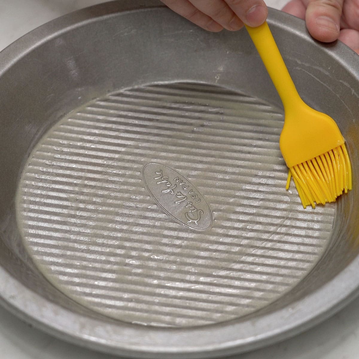 Greasing the pie pan with melted butter.