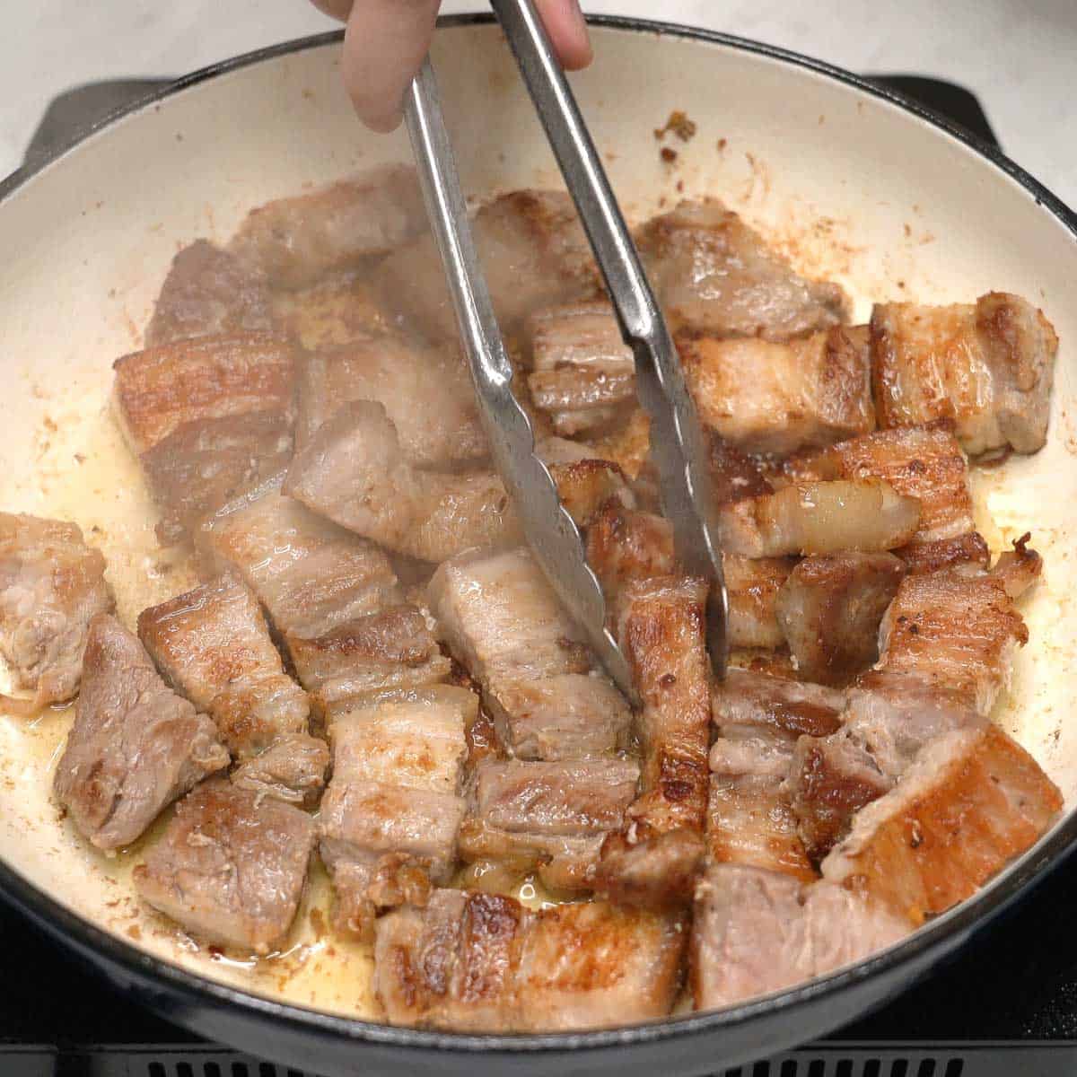 Searing pork in a pan.