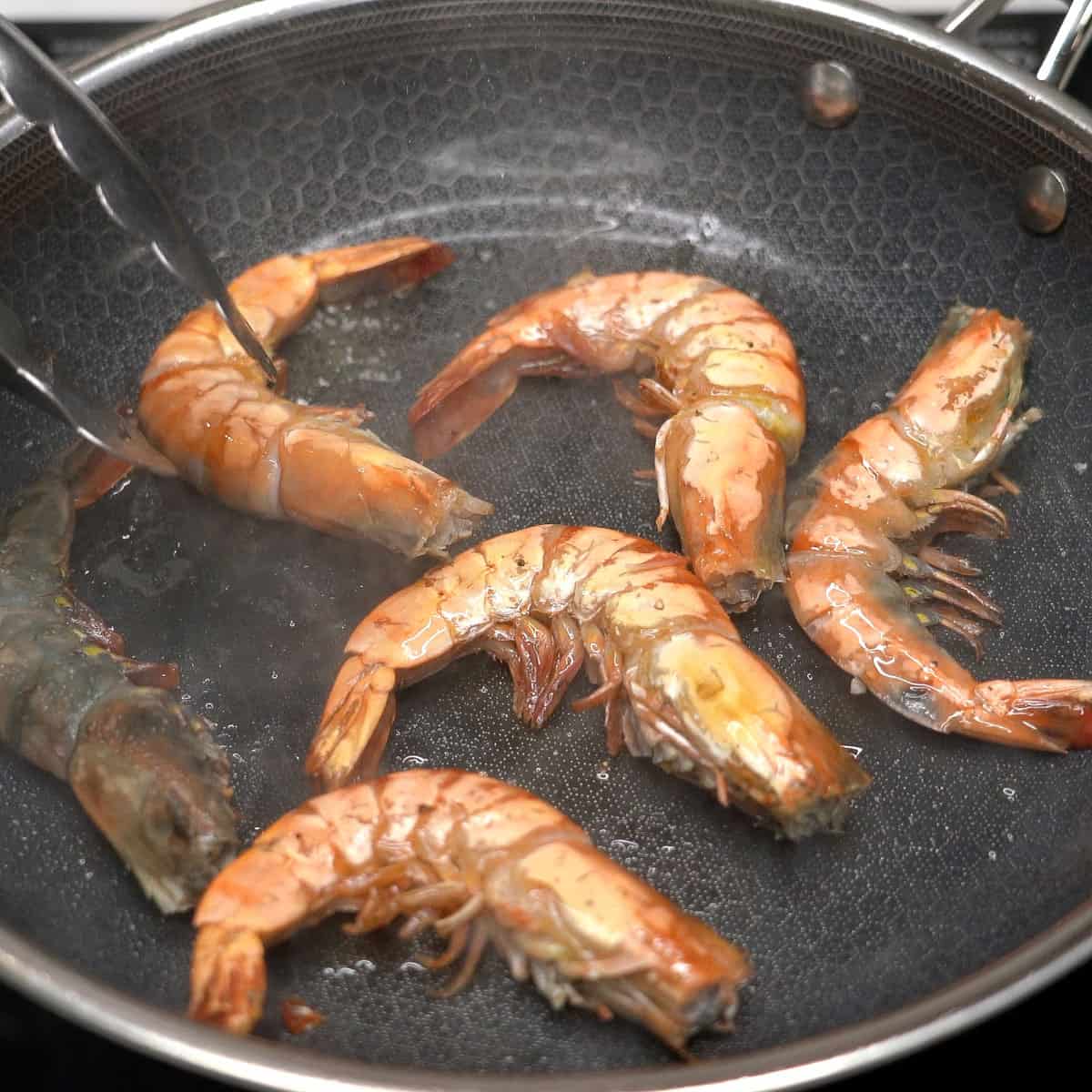 Searing shrimp in a wide pan.