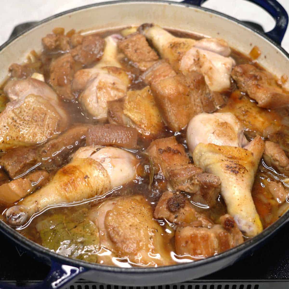 Simmering pork with chicken in a pan.