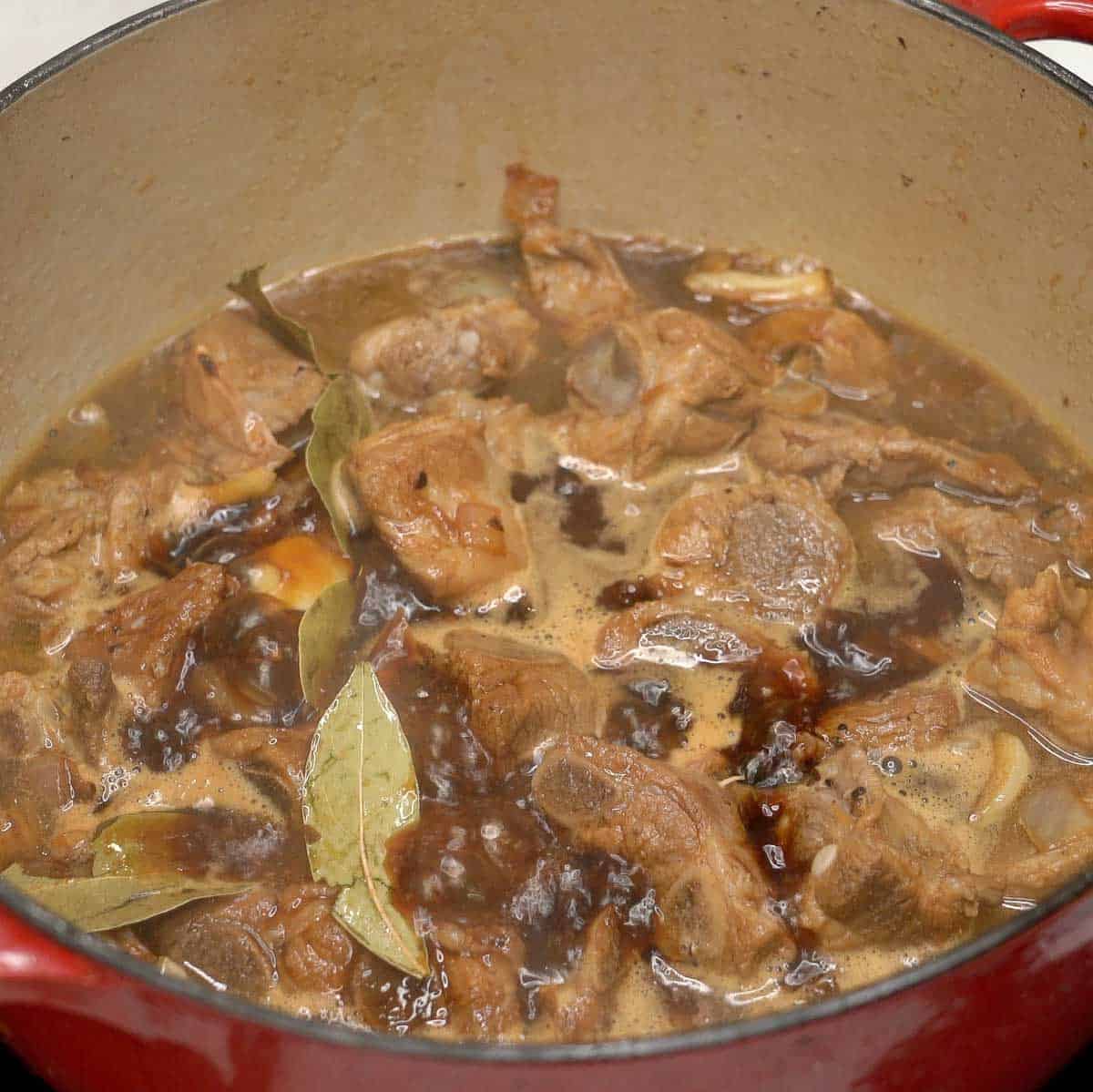 Simmering pork adobo ribs in a pot.