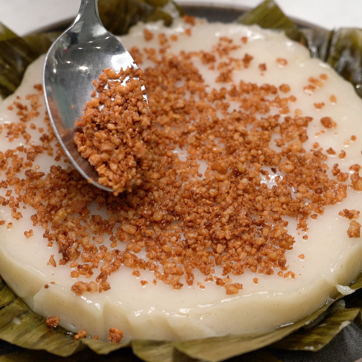 Adding latik on top of kalamay lansong.