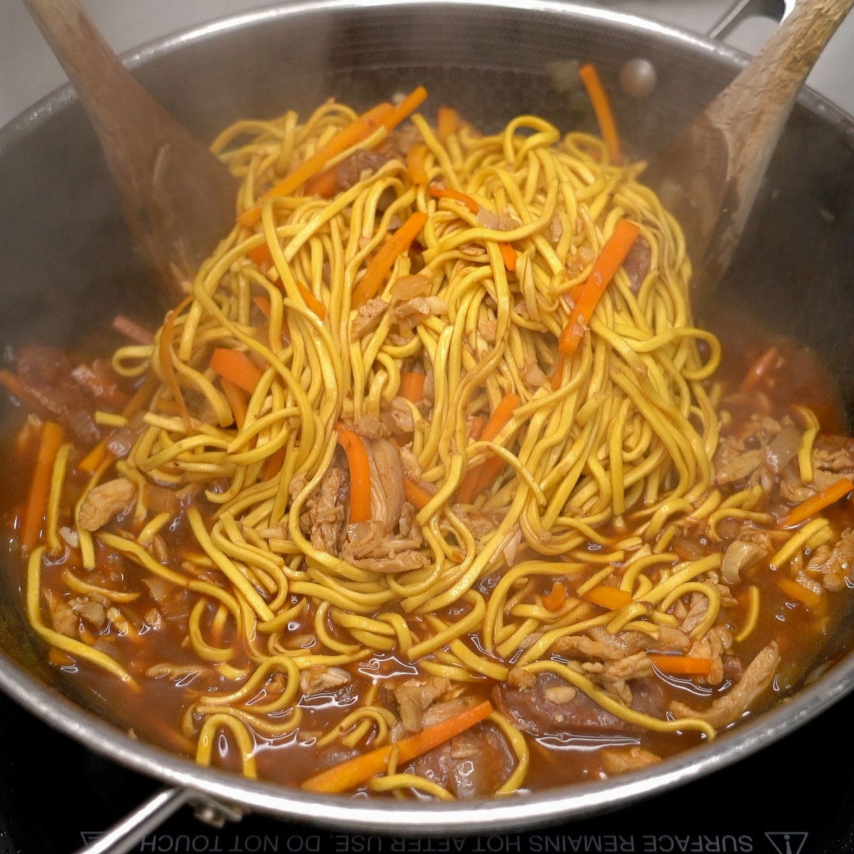 Tossing pancit canton noodles with the sauce in the pan.