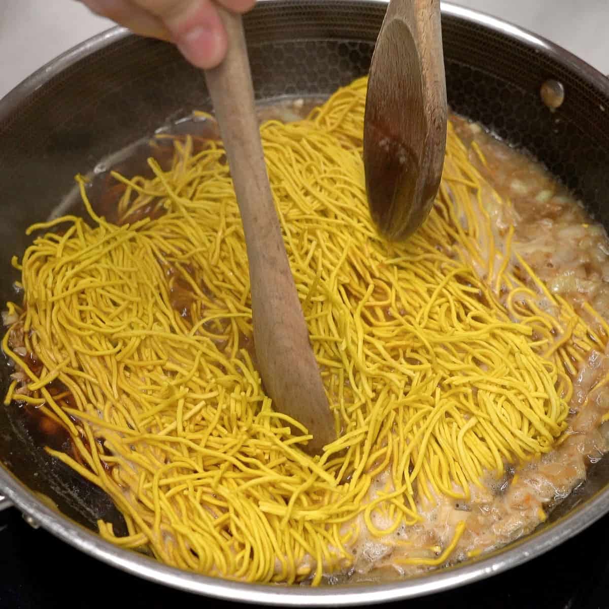 Tossing pancit bato noodles in the sauce.