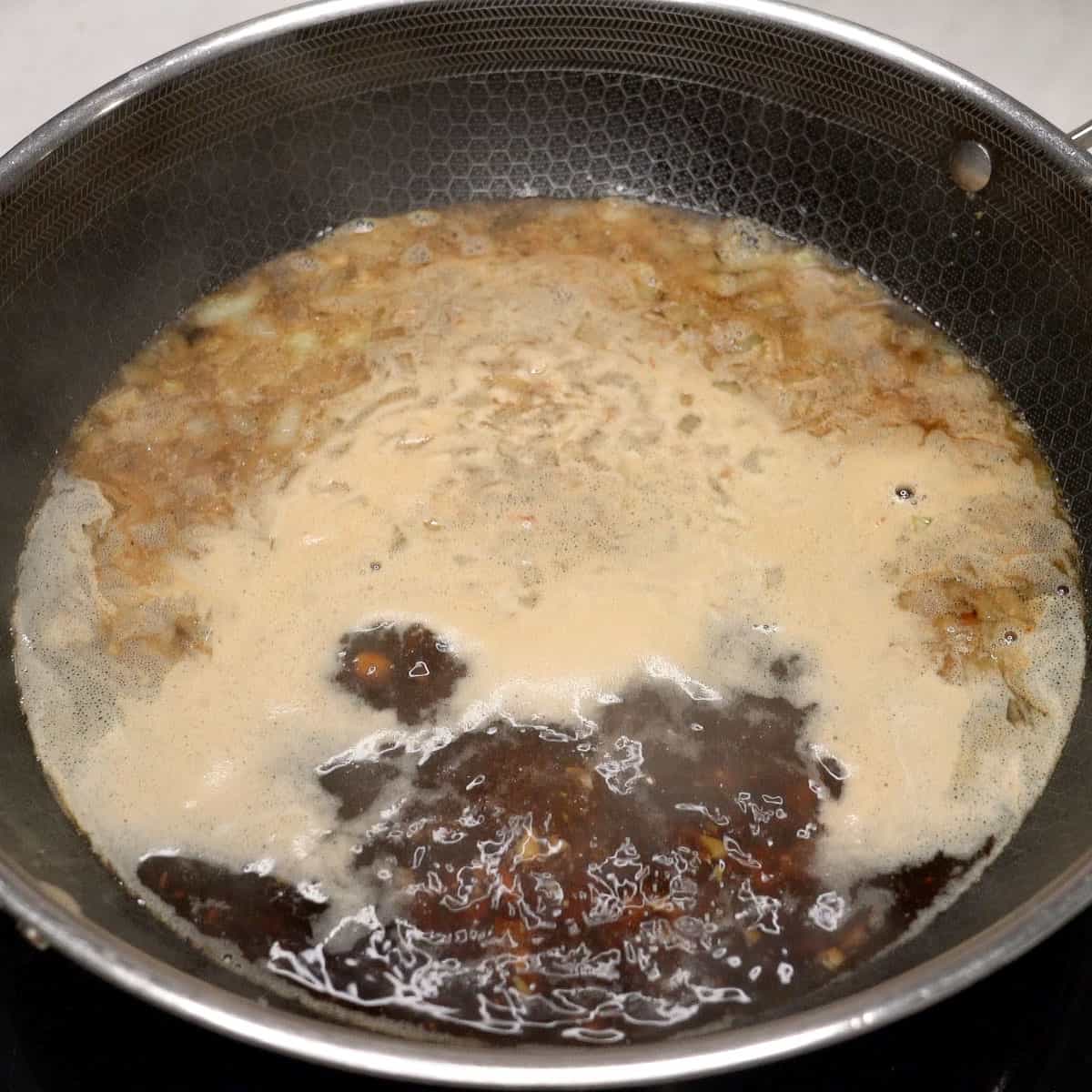 Boiling pancit bato sauce in a wok.