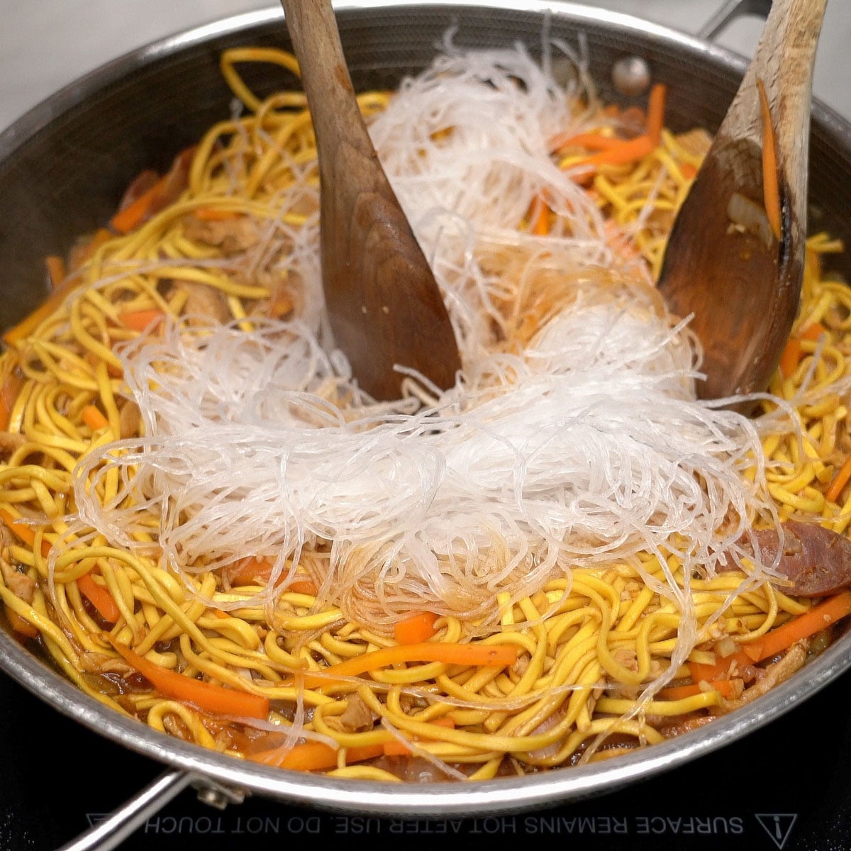 Mixing the sotanghon noodles with pancit canton noodles in the wok.