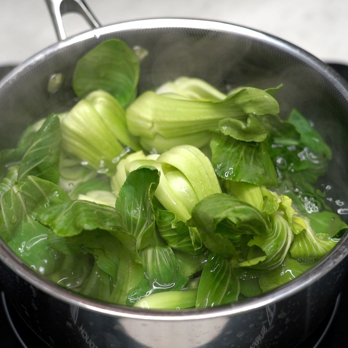 Blanching baby bok choy in a pot.