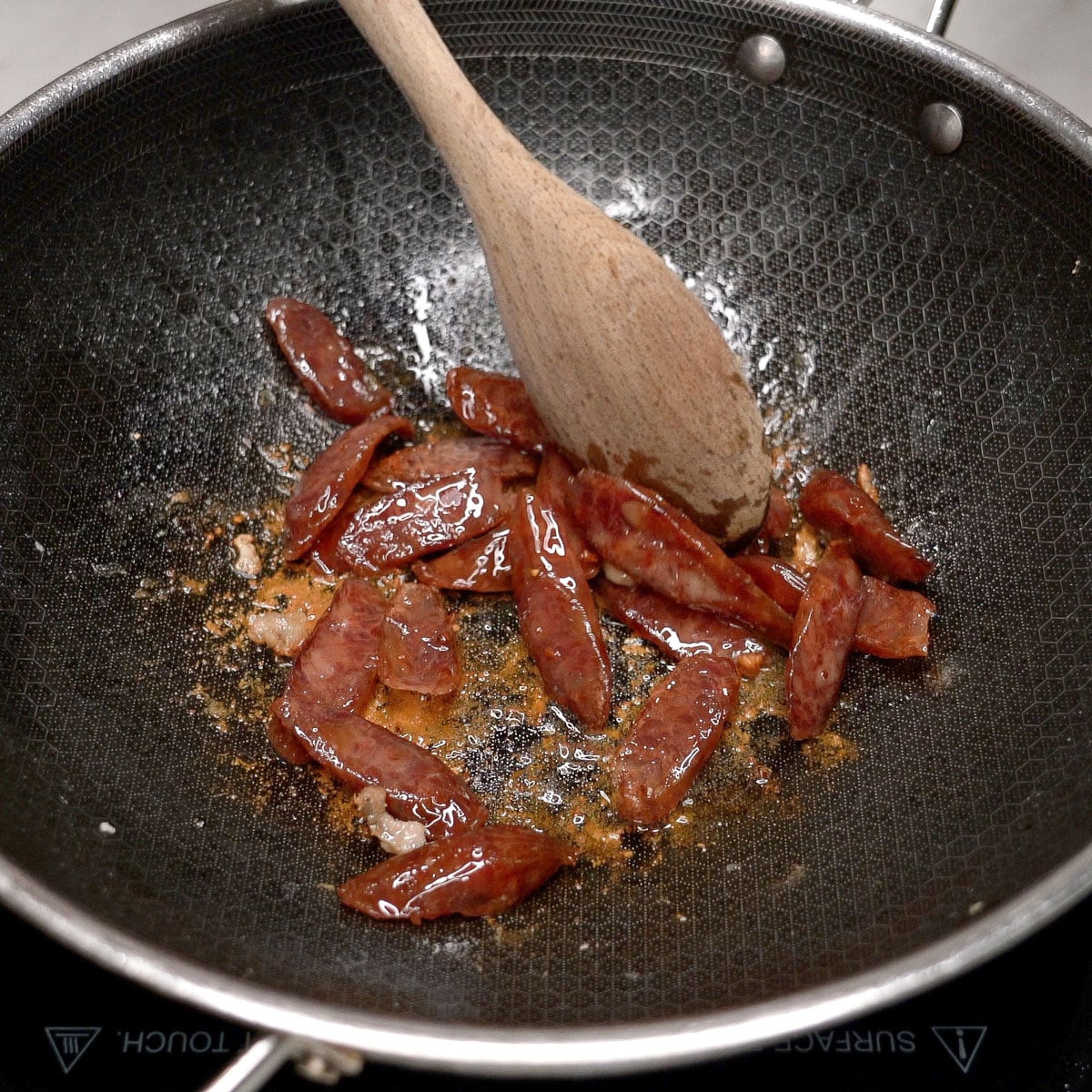 Cooking the Chinese sausage slices in the pan.