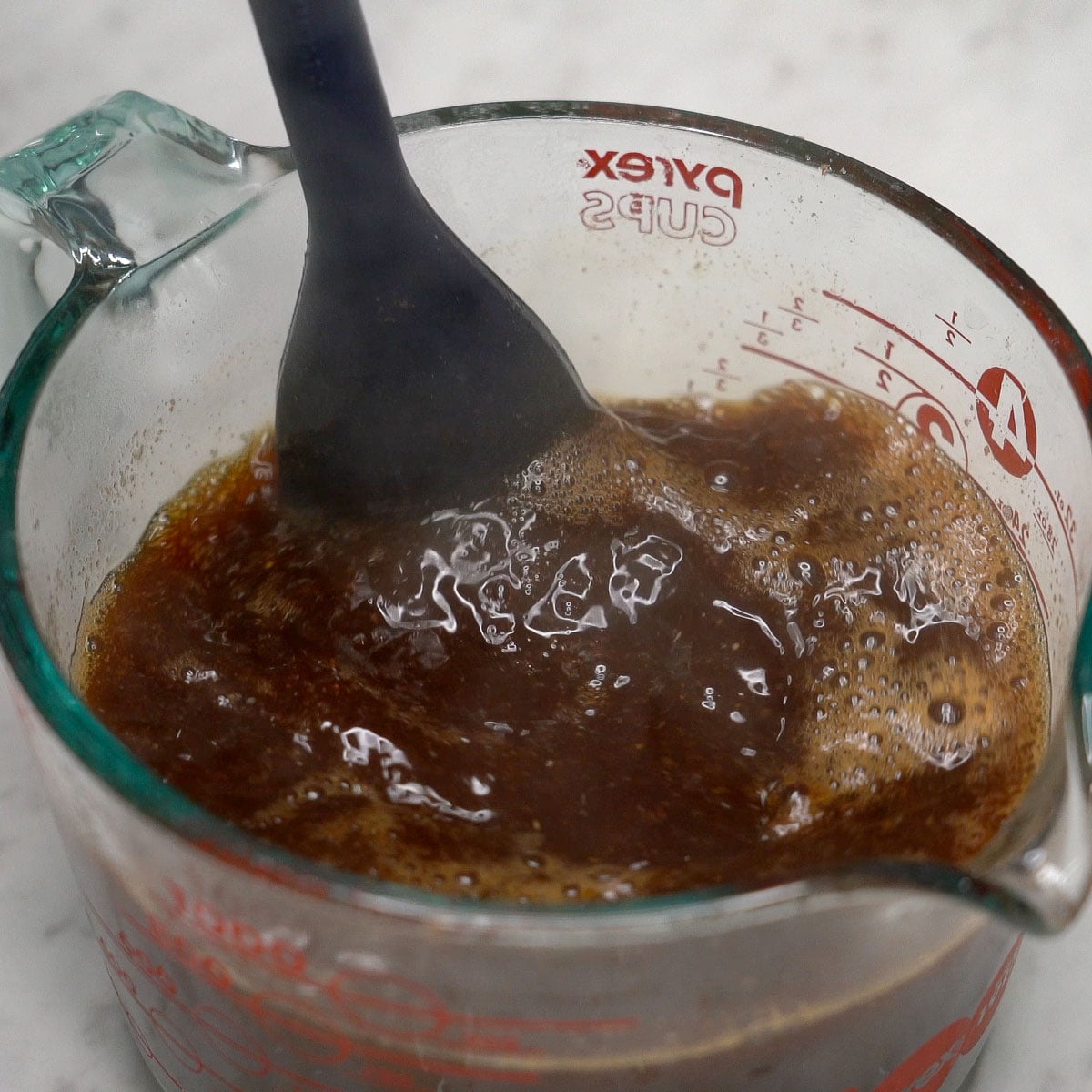 Mixing pancit chami sauce in a cup.