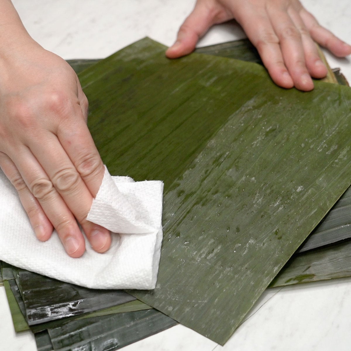 Wiping banana leaves with a paper towel.