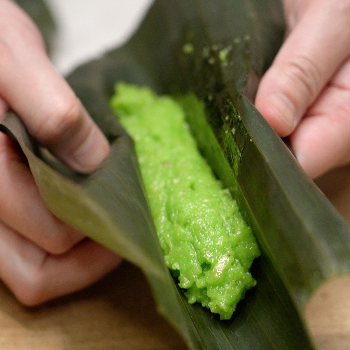 Rolling suman pinipig in a banana leaf.