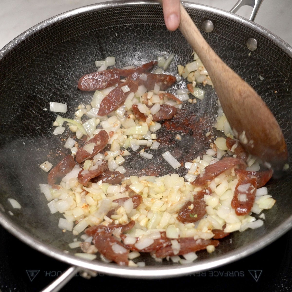 Sauteing the garlic and onion with the Chinese sausage in the pan.