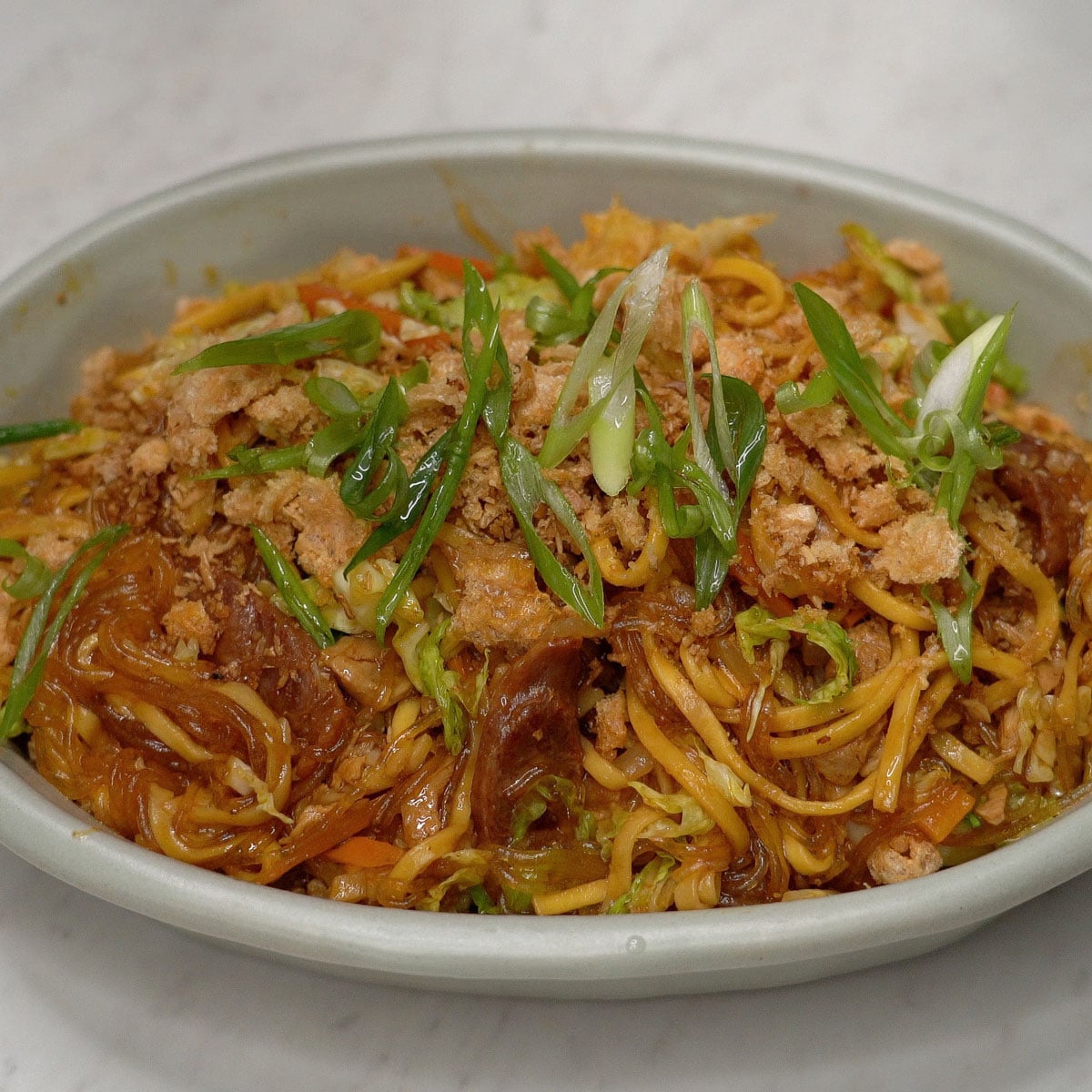 Pancit bam-i with carrots and cabbage, topped with chicharon and scallions.
