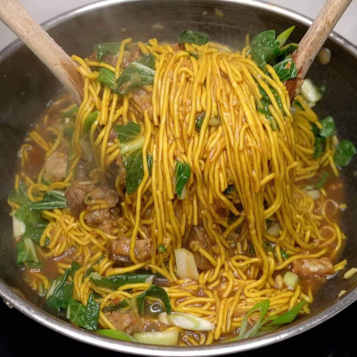 Tossing cooked pancit bato in a wok.