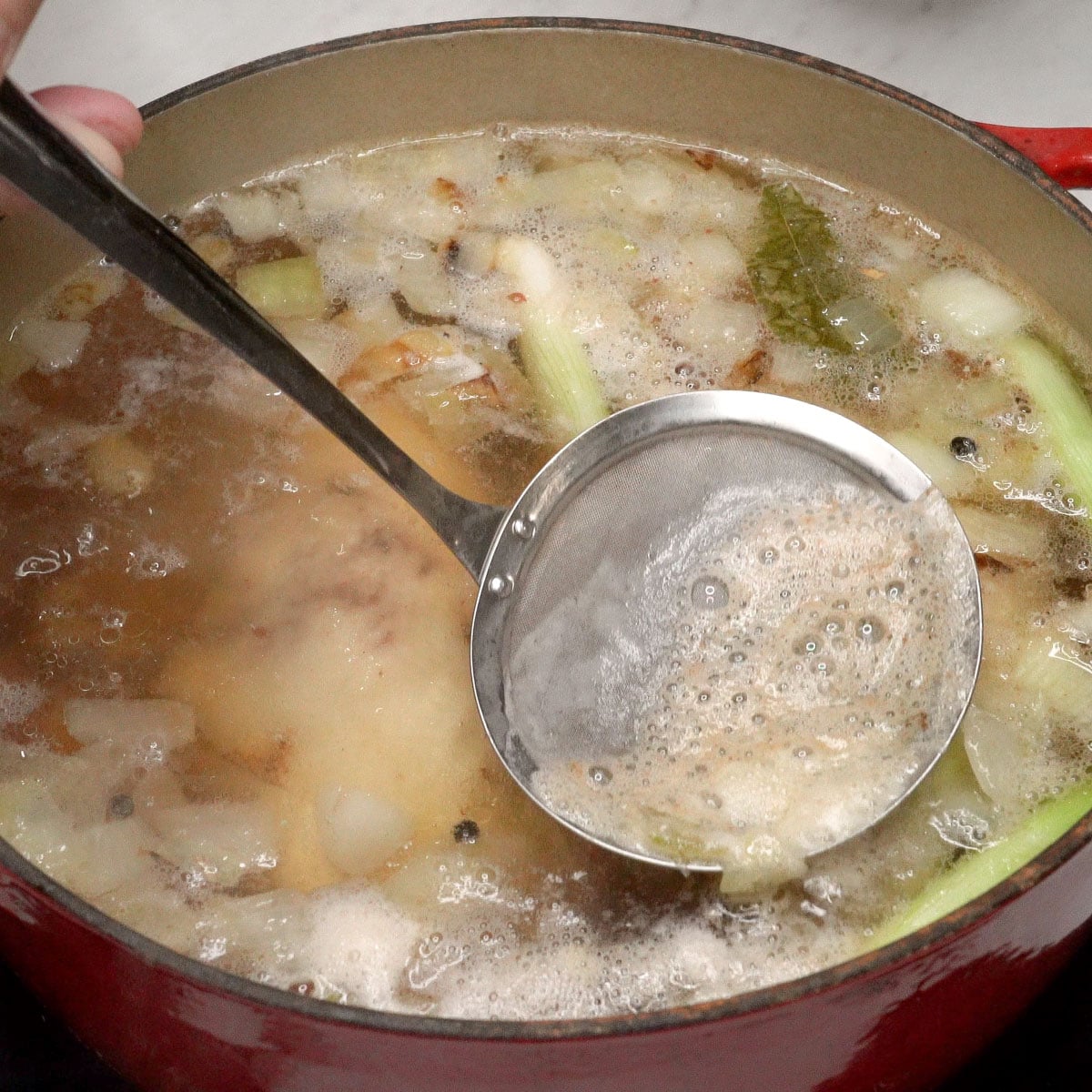 Skimming the foam that rises on top of the broth.
