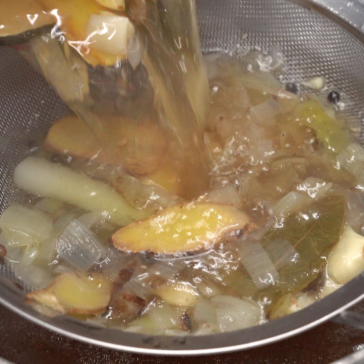 Straining the broth over a pot.