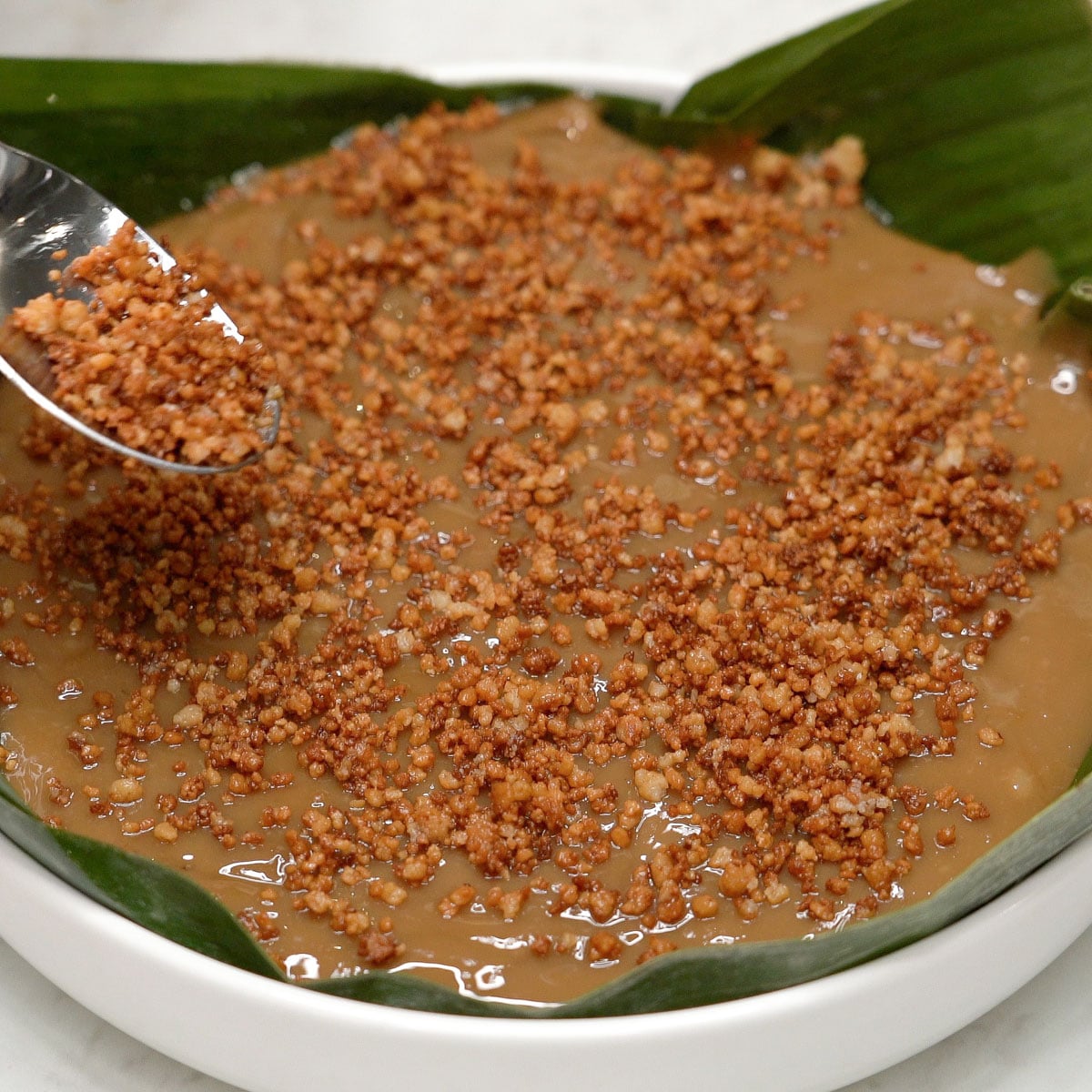 Adding latik on top of kalamay hati.