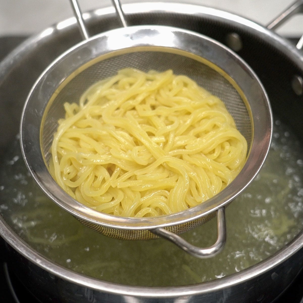 Cooked noodles in a strainer.