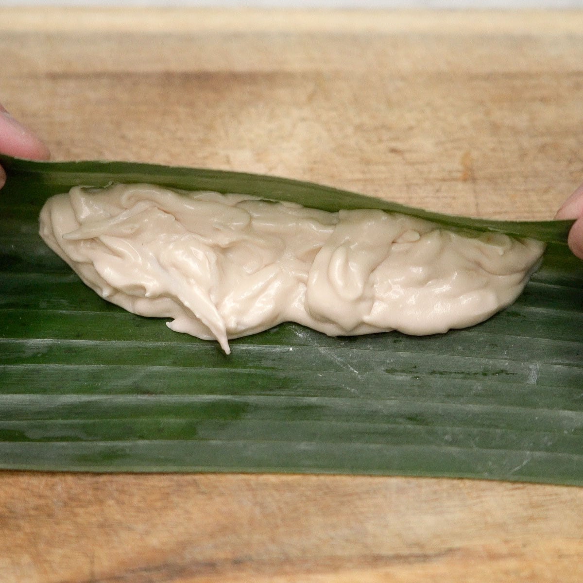 Rolling the banana leaf filled with tupig mixture.