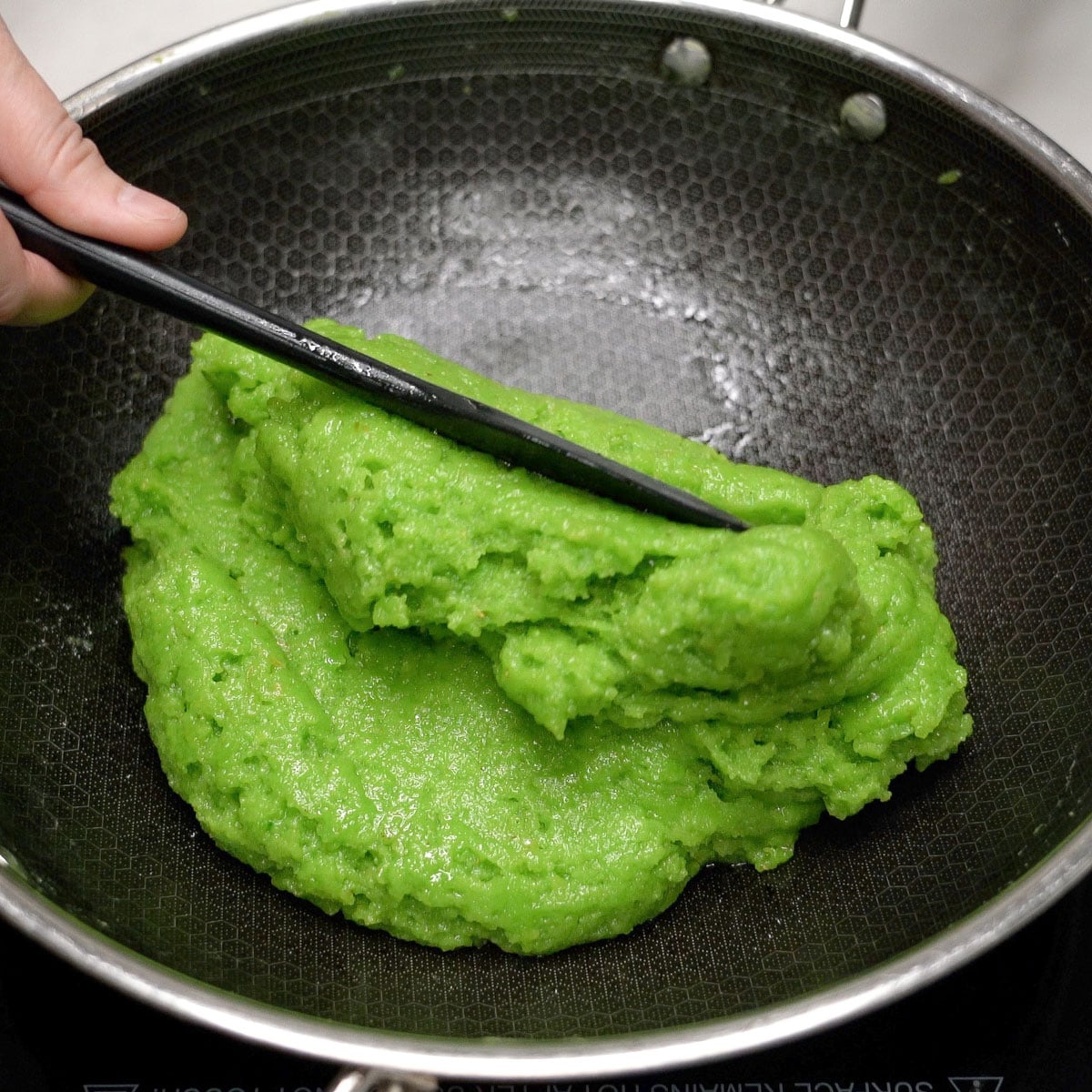 Mixing thickened bibingkang pinipig in a wok.