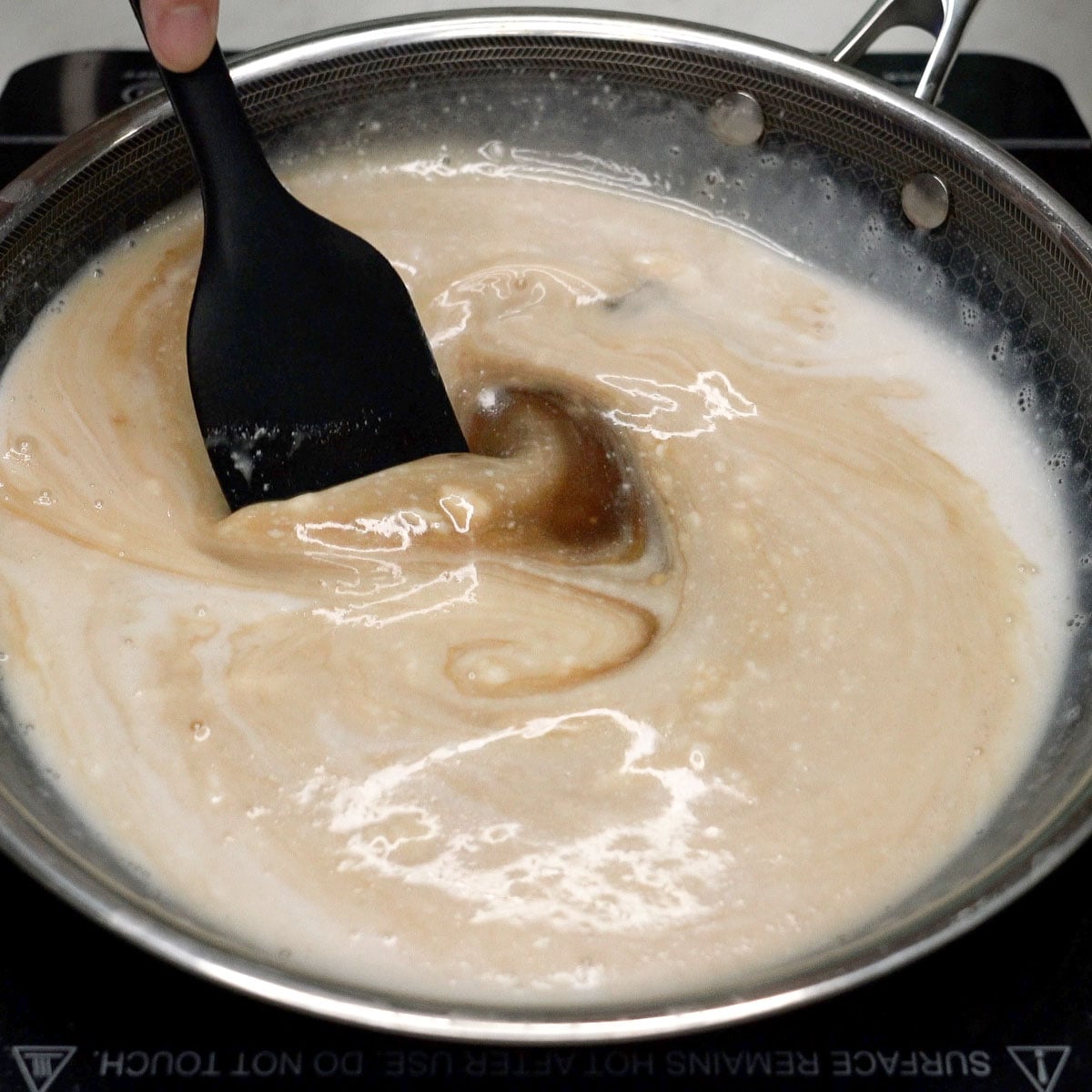 Mixing coconut cream and brown sugar in a wok.