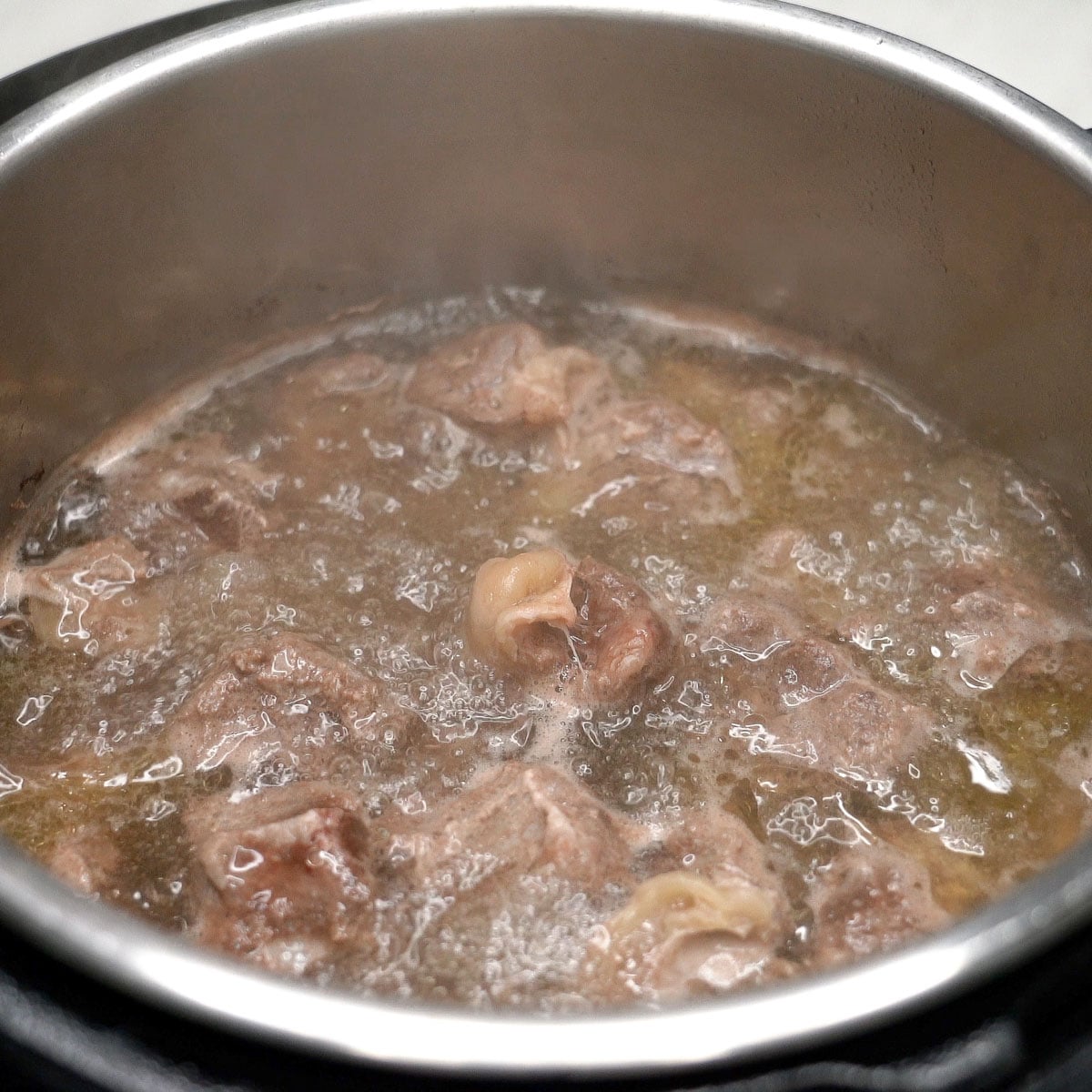 Parboiling the beef in a pot.