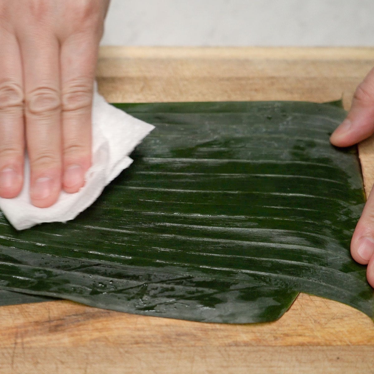Wiping banana leaves with a paper towel.