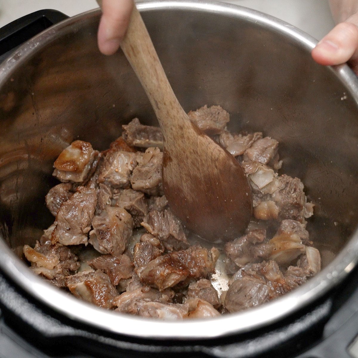 Searing the beef in a pot.