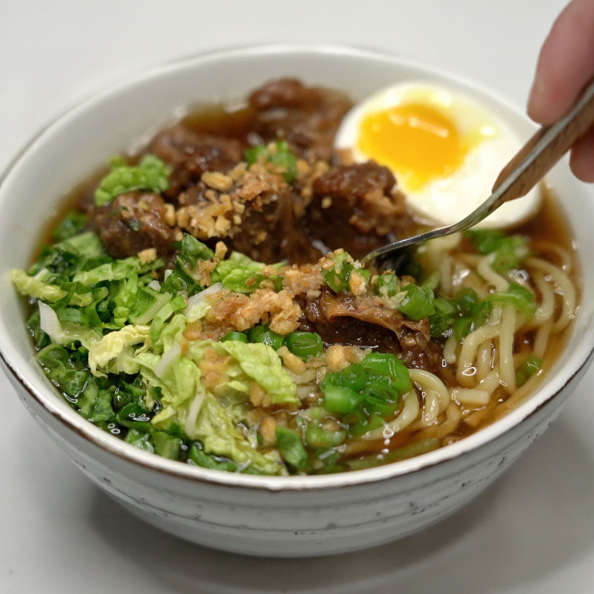Beef mami with egg, cabbage, green onions, and crispy garlic.