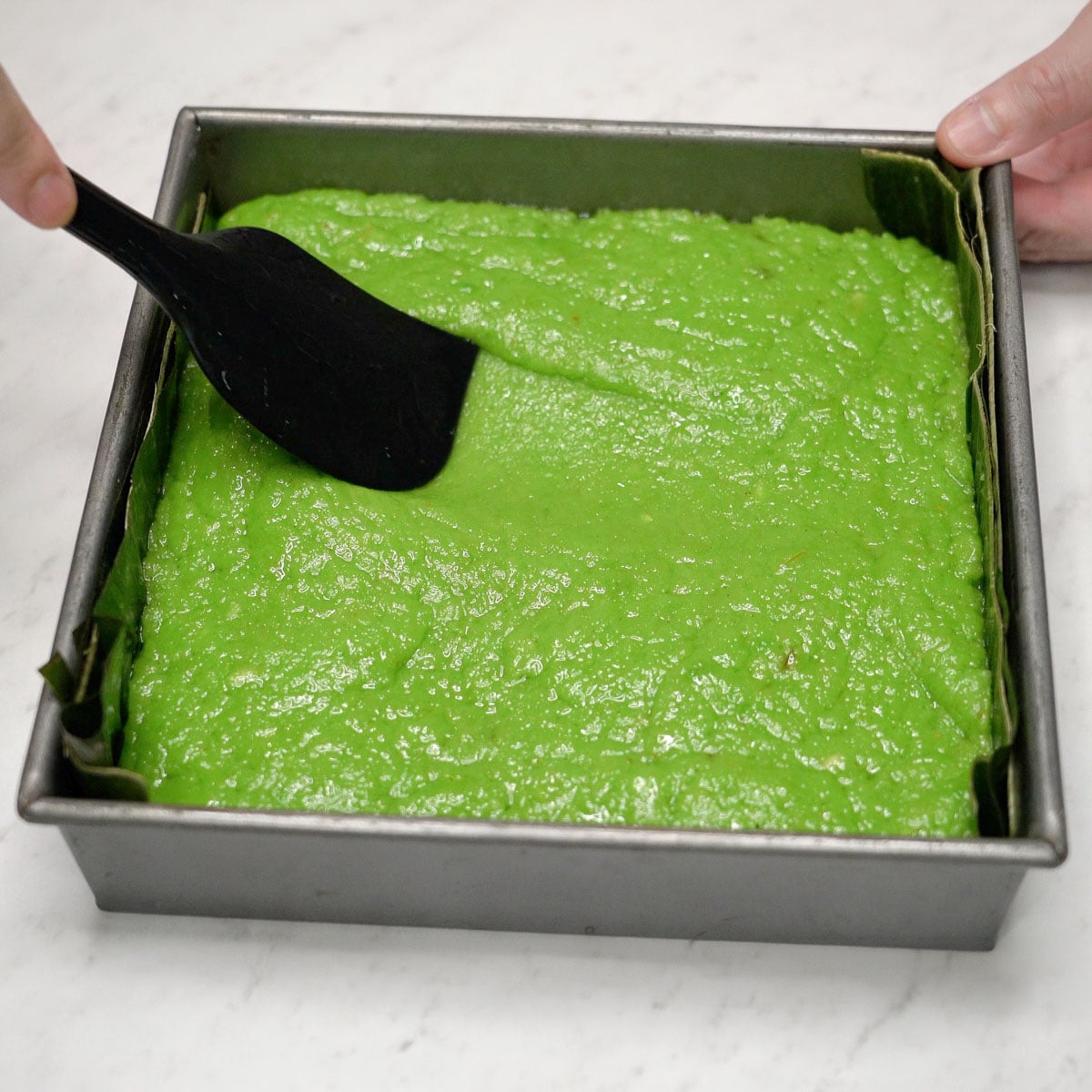 Spreading bibingkang pinipig base in a pan.