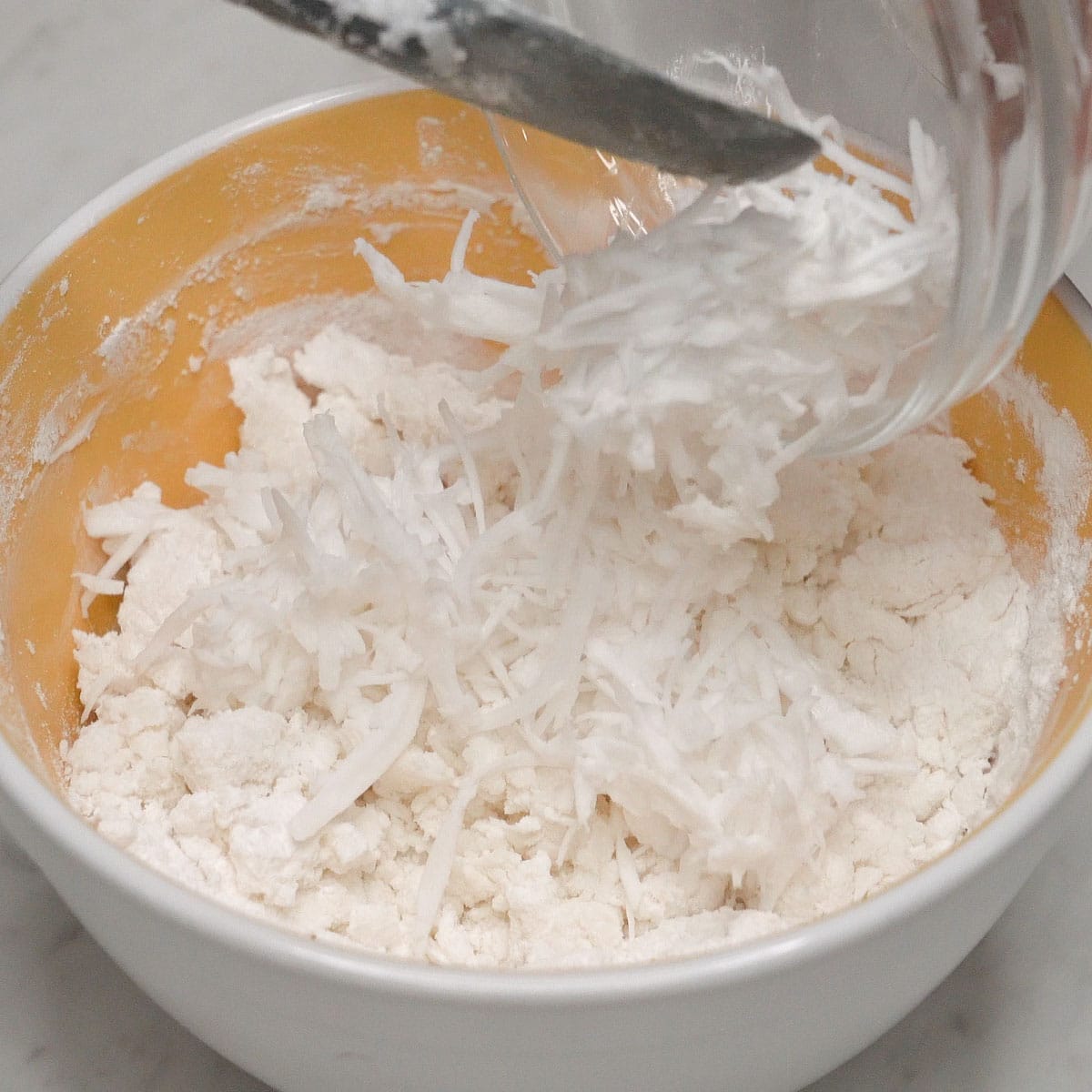 Adding grated coconut to the dough.
