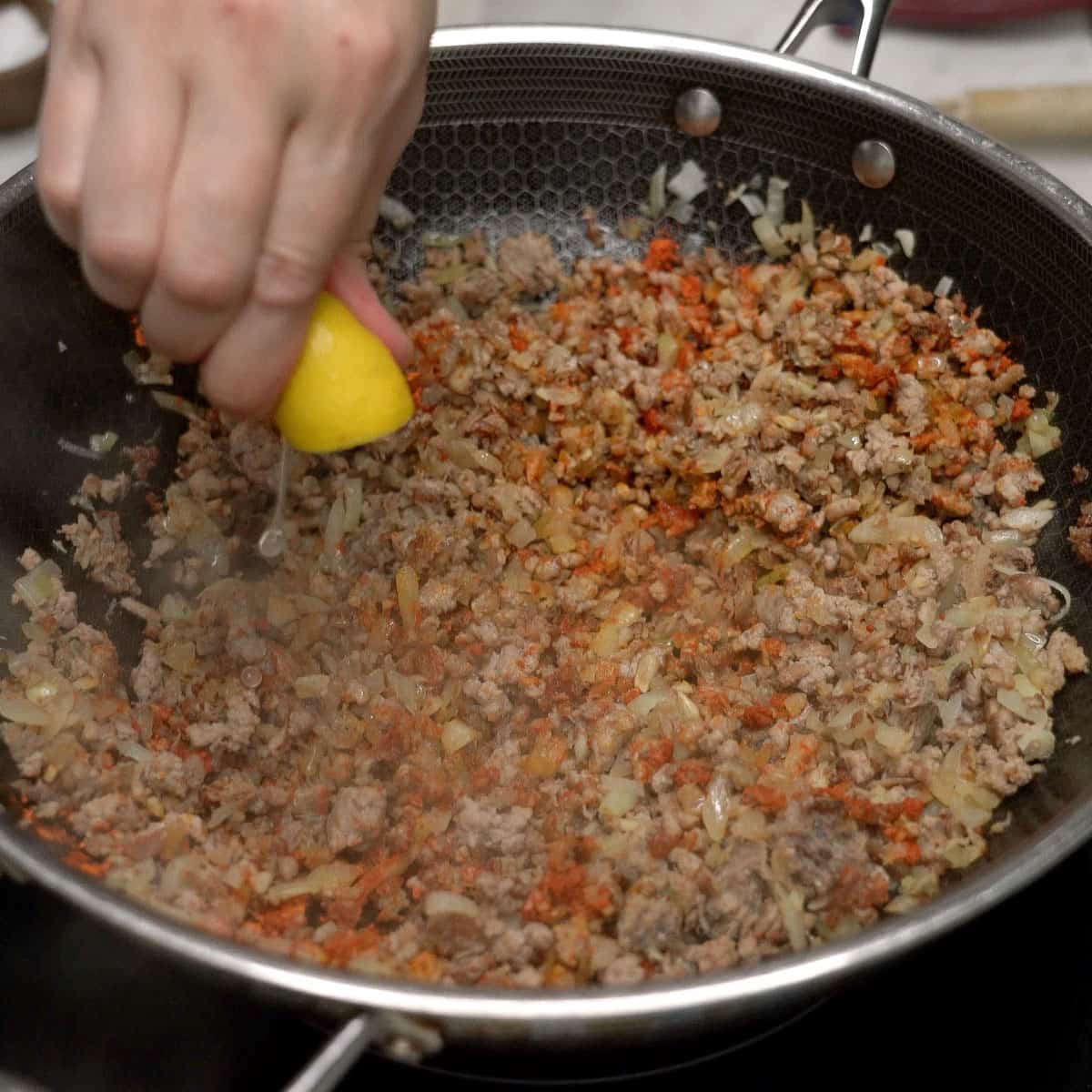 Squeezing lemon over the mixture in the wok.