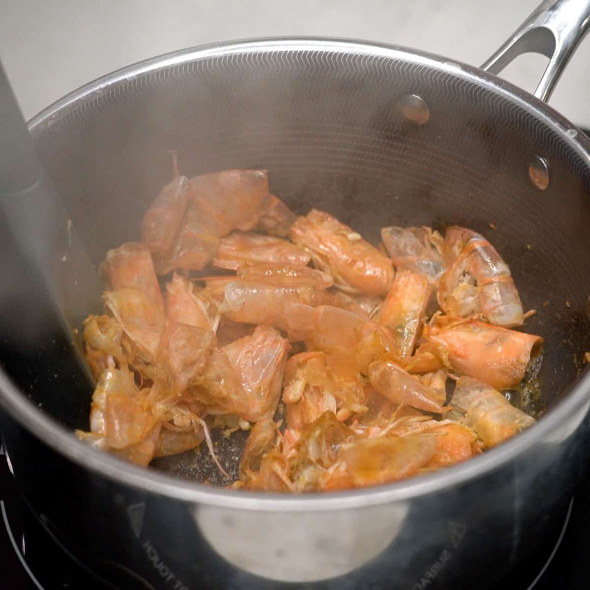 Browning shrimp heads and shells in the pot.