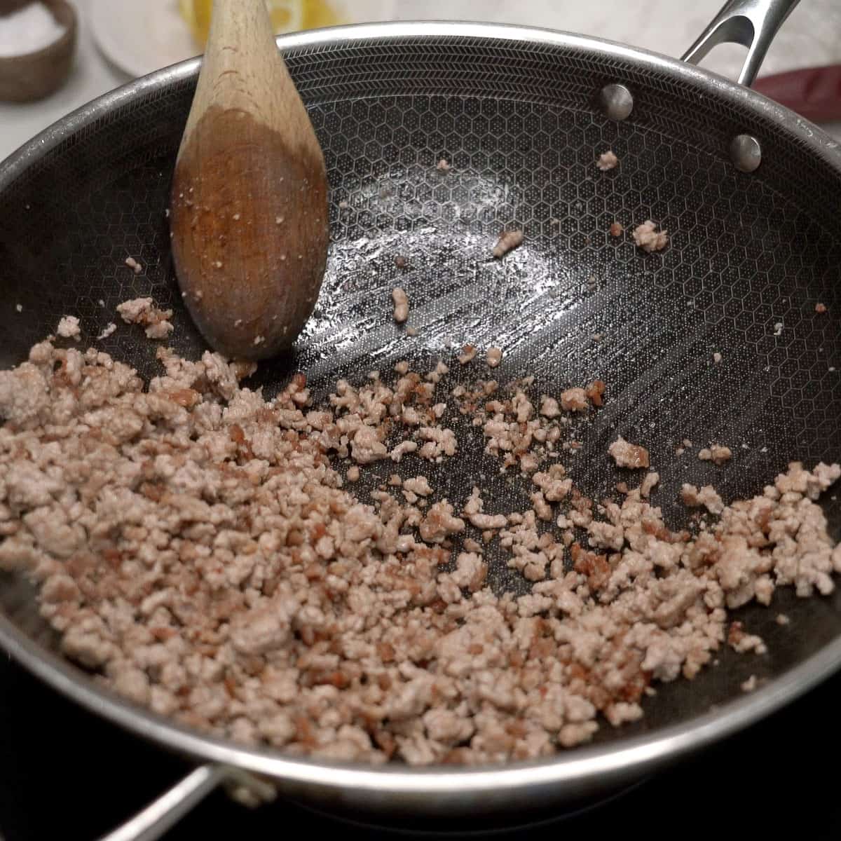 Browning ground pork in a wok.