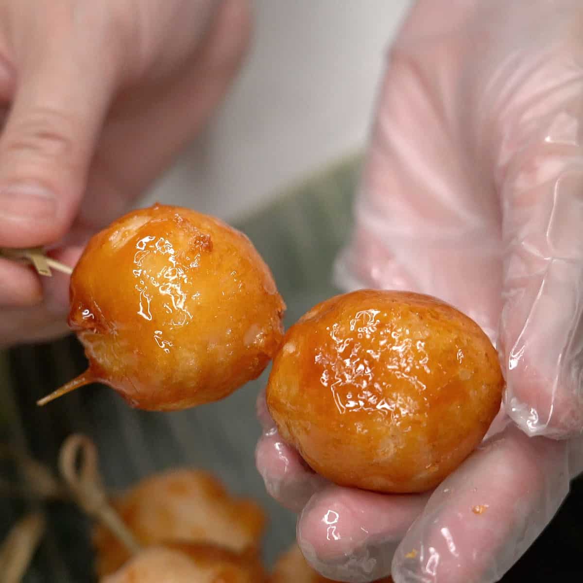 Threading the fried carioca balls onto skewers.