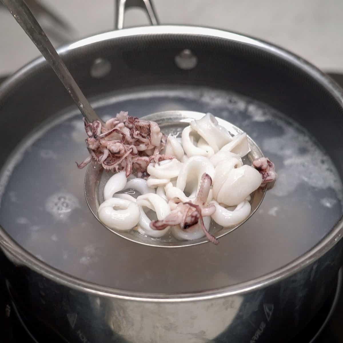 Straining the squid from the pot of water.