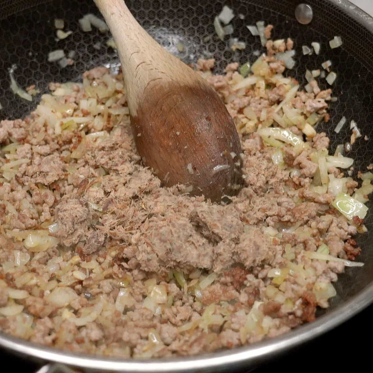 Mixing the smoked fish flakes into the pork and aromatics in the wok.