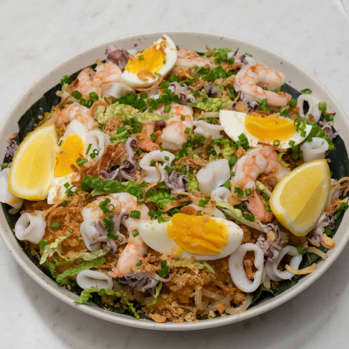 Pancit Malabon with toppings on a platter.